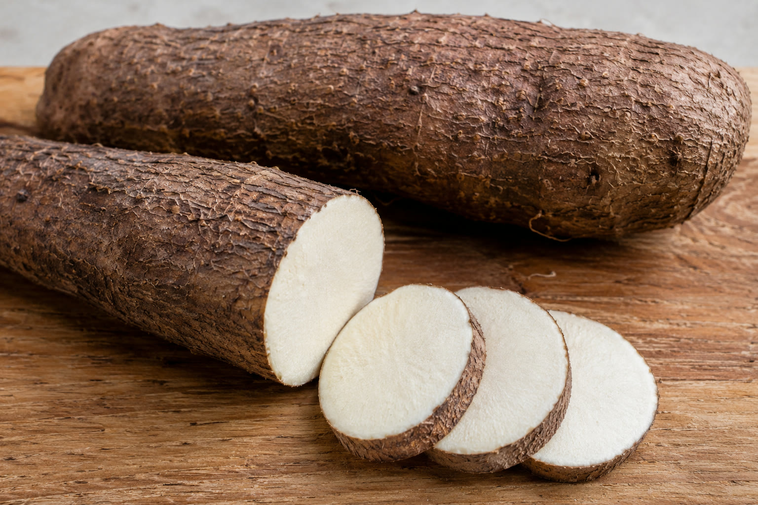 Whole and sliced yams of different varieties on a wooden board